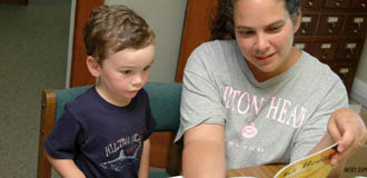 A boy reads a book with his parent for the summer reading program A boy reads a book with his parent for the summer reading program