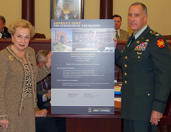Freeholder Directory Lillian Burry an d Col. Stephen Christian hold up a poster affirming partnership with Fort Monmouth and the community